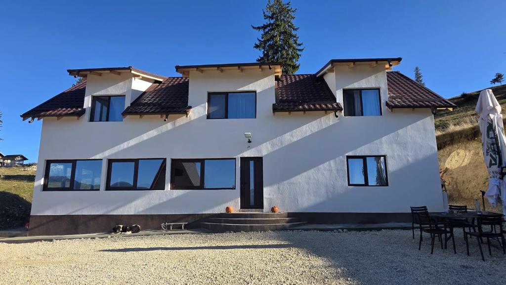 a large white house with black windows at Pensiunea Heaven in Dîmbovicioara