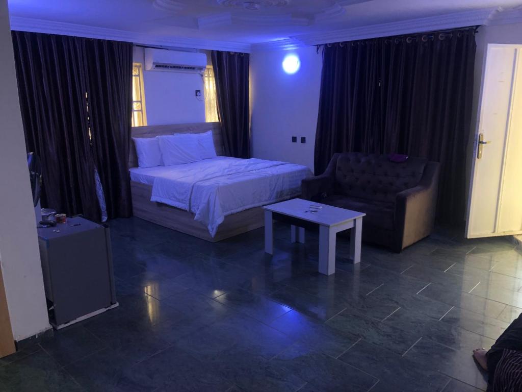 Un dormitorio con una cama, un sofá y una mesa. en Noblelite Hotels, en Gwarinpa