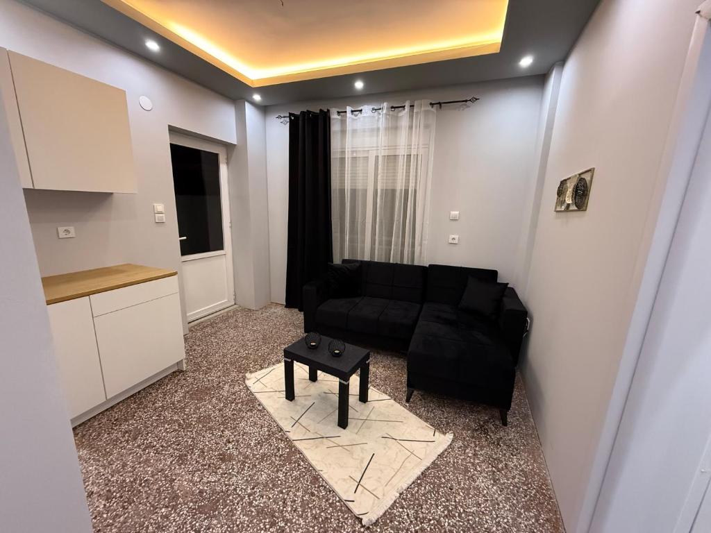 Una sala de estar con un sofá negro y una mesa. en Masal home, en Alexandroupoli