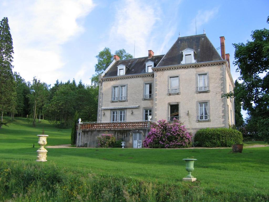 una casa grande en un campo verde con árboles en Domaine de Gaudon, en Ceilloux