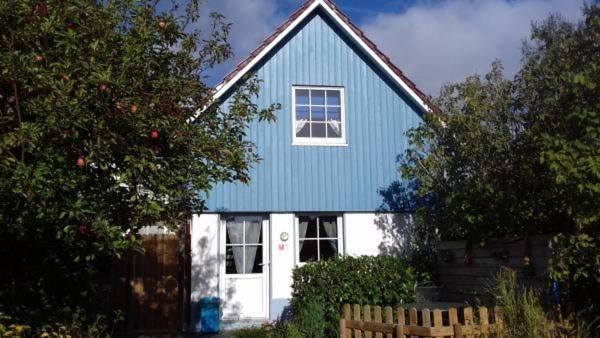 une maison bleue et blanche avec une porte blanche dans l'établissement Friesenhuus, à Butjadingen