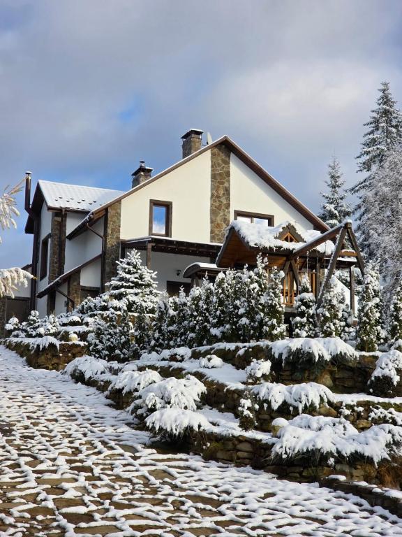 a house covered in snow in front of a stone path at Шале 5 Стефанія in Mykulychyn