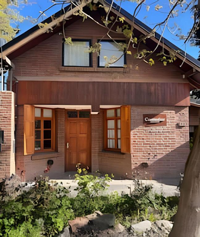 a house with a brown door and a window at CosmoSur - Centro El Bolson in El Bolsón