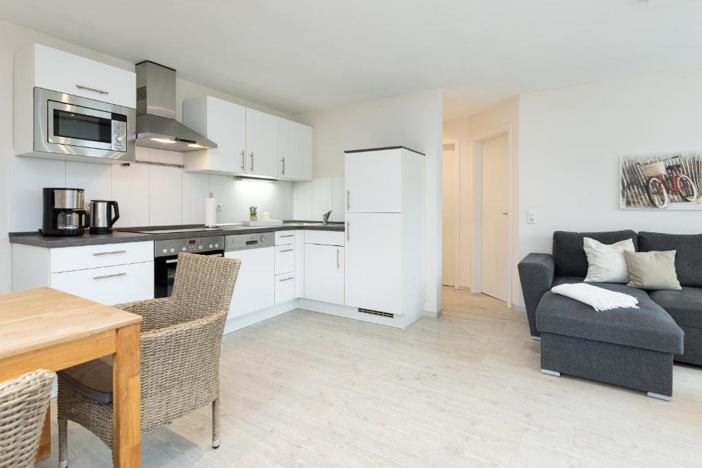 a kitchen and living room with a couch and a table at D4 Bungalow - Haus Dünenpark Königsberger Allee 12 - FERIENDOMIZIL HOLLICH in Grömitz