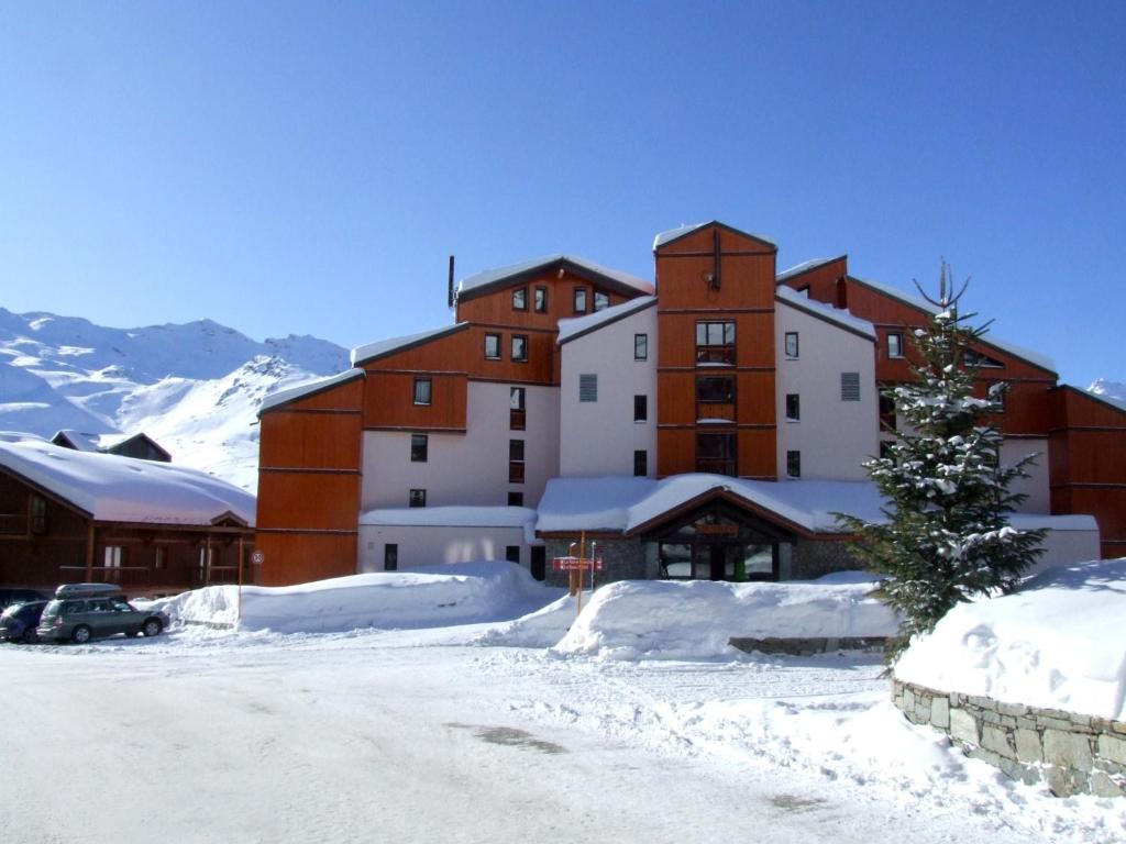 ein großes Gebäude im Schnee mit einem Weihnachtsbaum in der Unterkunft Joker Appartements VTI in Val Thorens