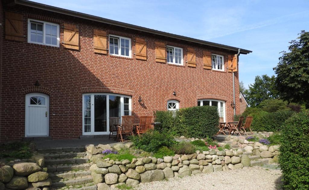 ein rotes Backsteinhaus mit einem Steingarten davor in der Unterkunft Hof Rüsch - FeWo Bökenacker in Kesdorf