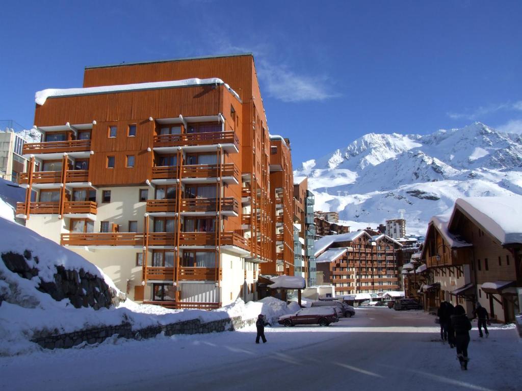 un bâtiment dans la neige à côté d'une montagne dans l'établissement Lauzieres Appartements VTI, à Val Thorens