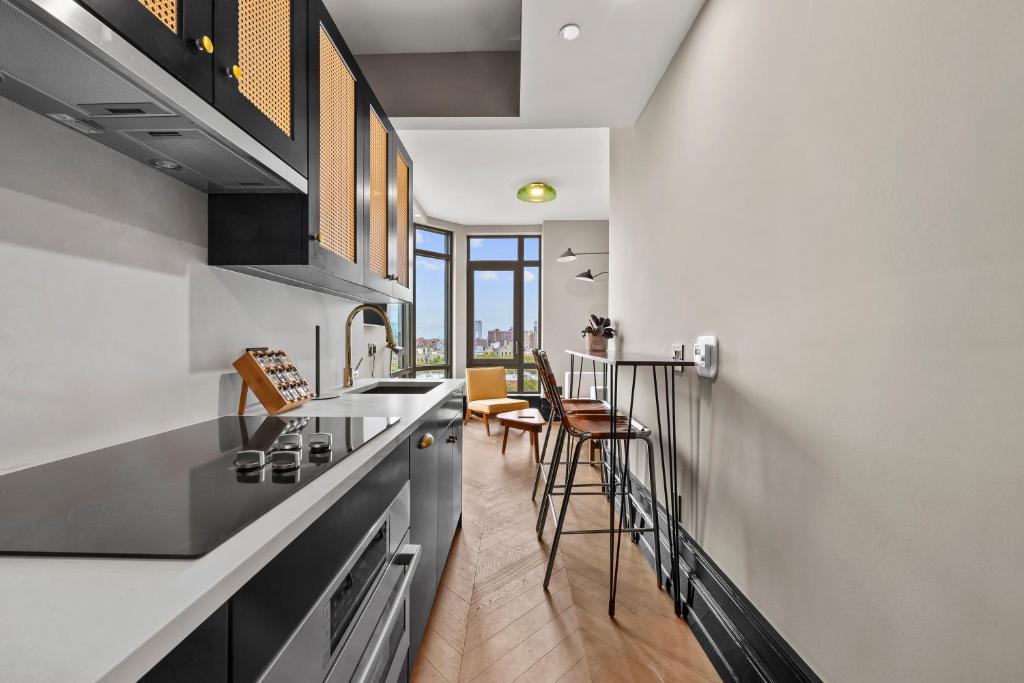 cocina con paredes blancas, barra y sillas en Freeman 903 by Rove 1BR Condo with Shared Amenities, en Nueva York