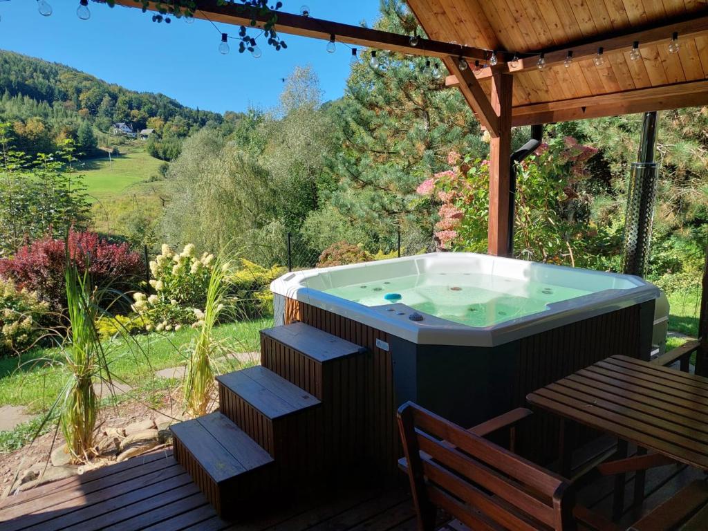 a hot tub on a wooden deck with a bench at Domek za lasem in Laskowa