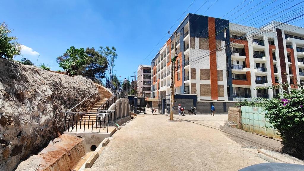 eine Stadtstraße mit einem Gebäude und einer Steinmauer in der Unterkunft One Bedroom Apartment near KSG - Arc II in Nairobi