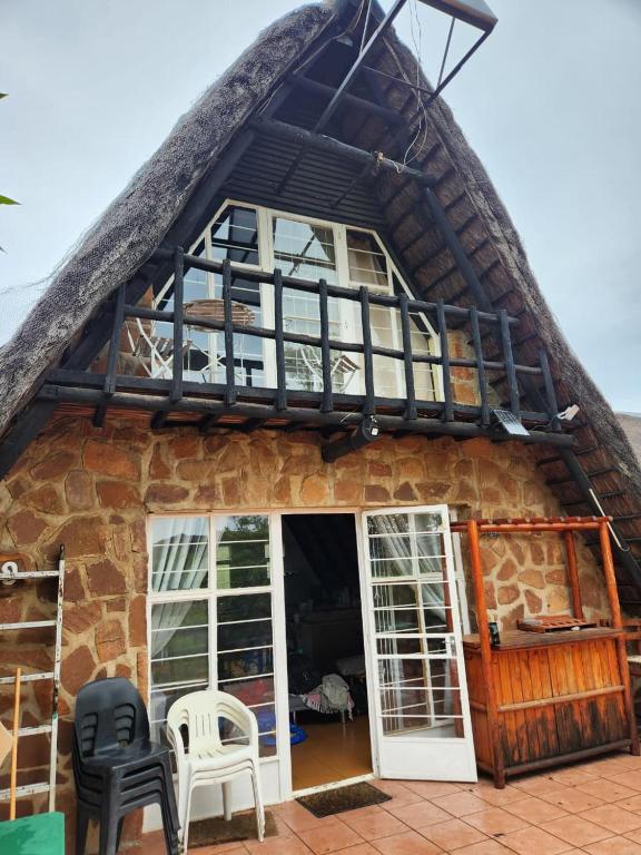 a house with a thatched roof with chairs outside at Amanda's Retreat in Buffelspoort
