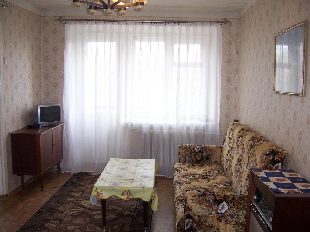 ヤロスラヴリにあるApartment Pisemskogo 46のリビングルーム(ソファ、テーブル付)、窓が備わります。