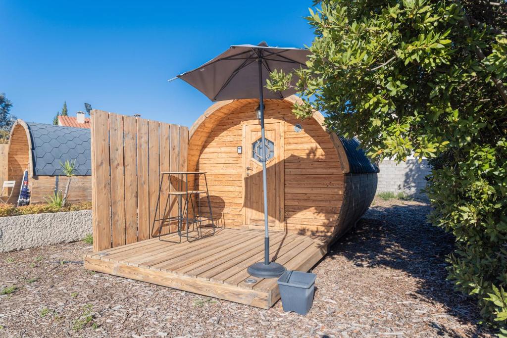 un ponte di legno con un ombrellone e una sedia sopra di Barrel Orange a Saint-André