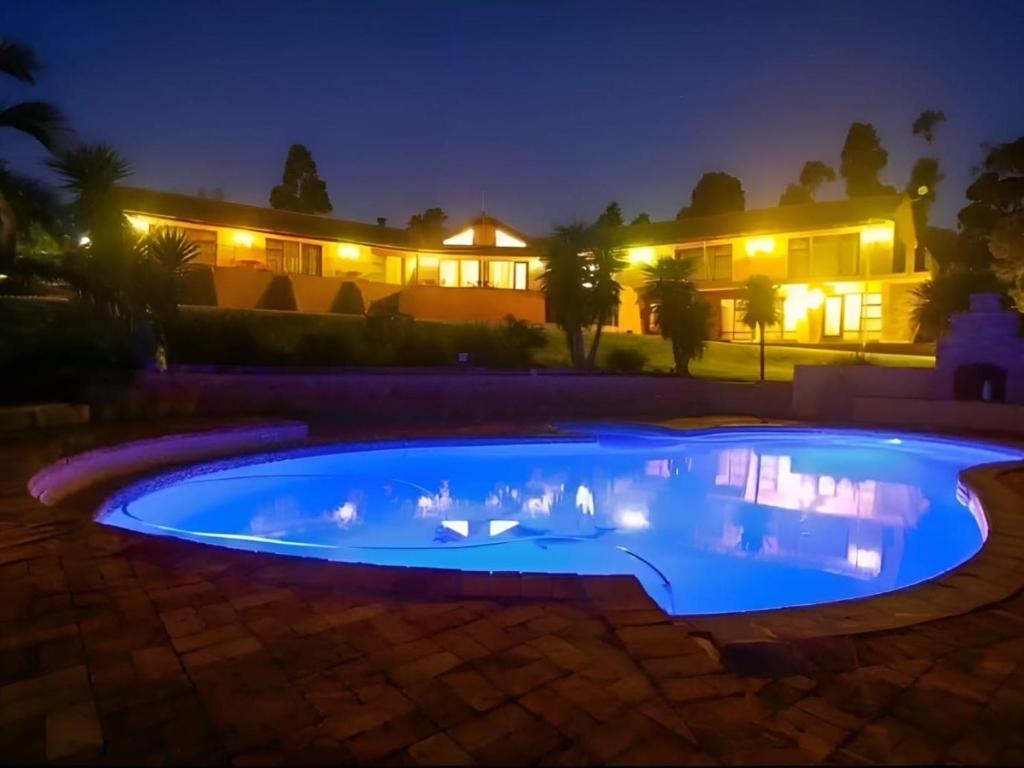ein Schwimmbad in der Nacht mit einem Haus im Hintergrund in der Unterkunft Into the Sunset Manor in Gordonʼs Bay