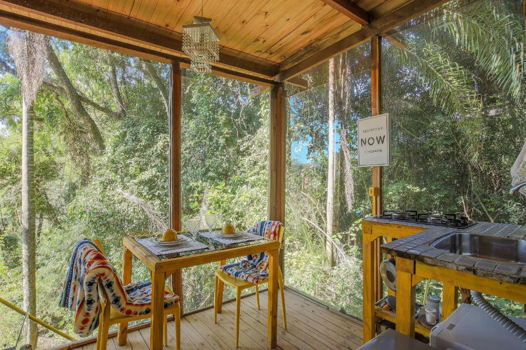 eine abgeschirmte Veranda mit einem Tisch und Stühlen darauf in der Unterkunft Casa de Vidro 2, há 90km de São Paulo, com Lago, Piscina, Caiaque, Stand UP, Cascata e Escorrega no Lago - Quinta do Vale Itatiba in Itatiba