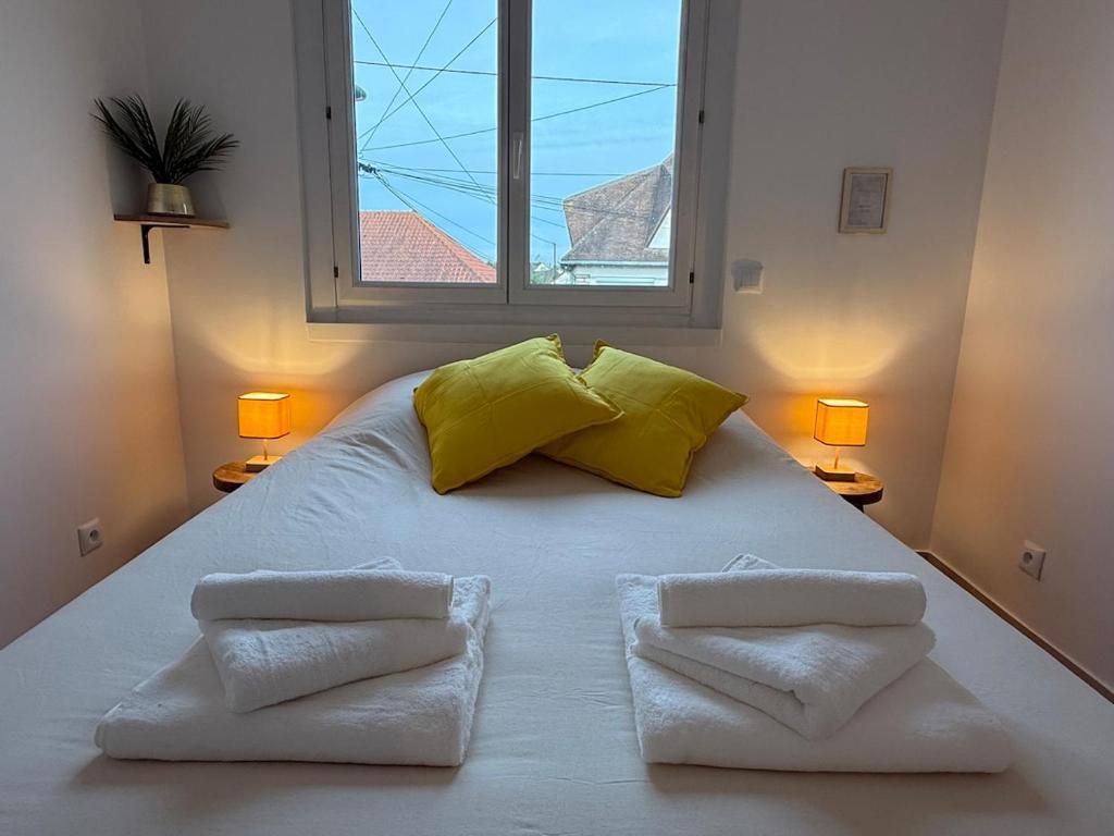 un grand lit blanc avec deux oreillers et une fenêtre dans l'établissement Magnifique T3 proche Paris & Disneyland, à Ozoir-la-Ferrière