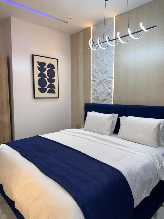 Un dormitorio con una cama azul y blanca con una lámpara de araña. en Pavilion Heights, en Lagos