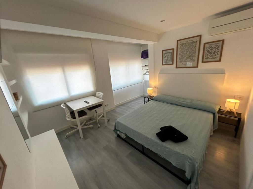 a bedroom with a bed and a table and two windows at Rooms Mármol, junto a Puerta Toledo in Madrid