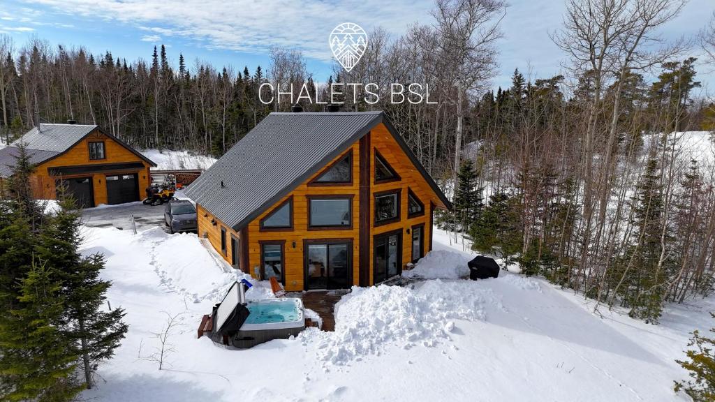 a log cabin in the snow with a car in front at Chalets BSL in Saint-Simon-de-Rimouski