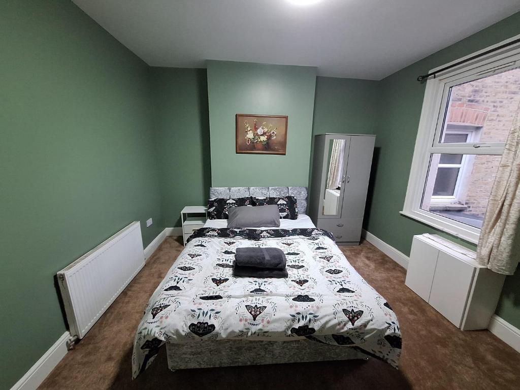 a bedroom with a bed in a green room at home from home 2 bed flat in Kingston upon Thames