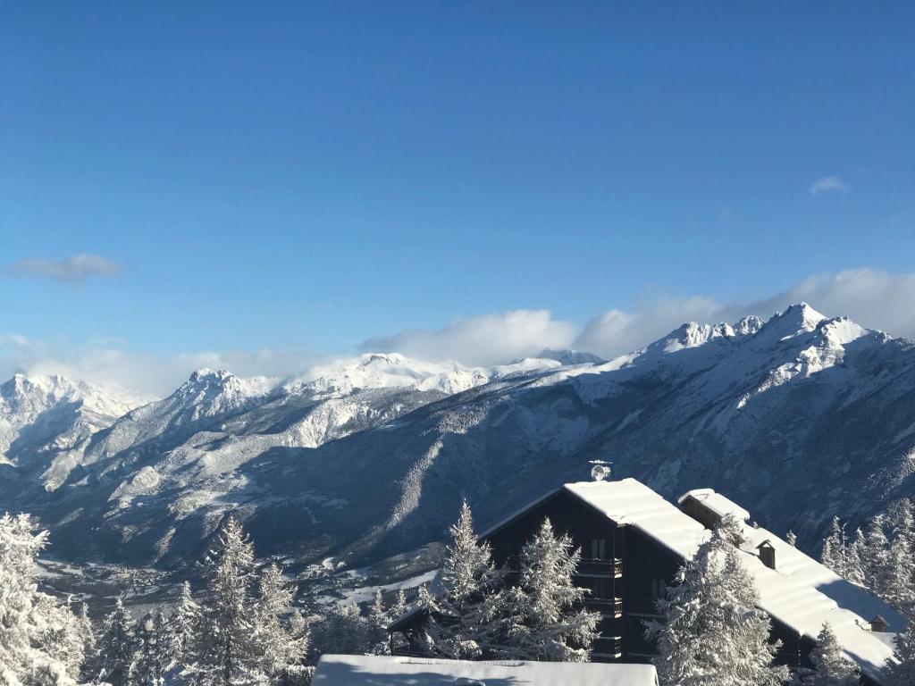 un lodge de ski avec des montagnes enneigées en arrière-plan dans l'établissement Montagne, à Risoul