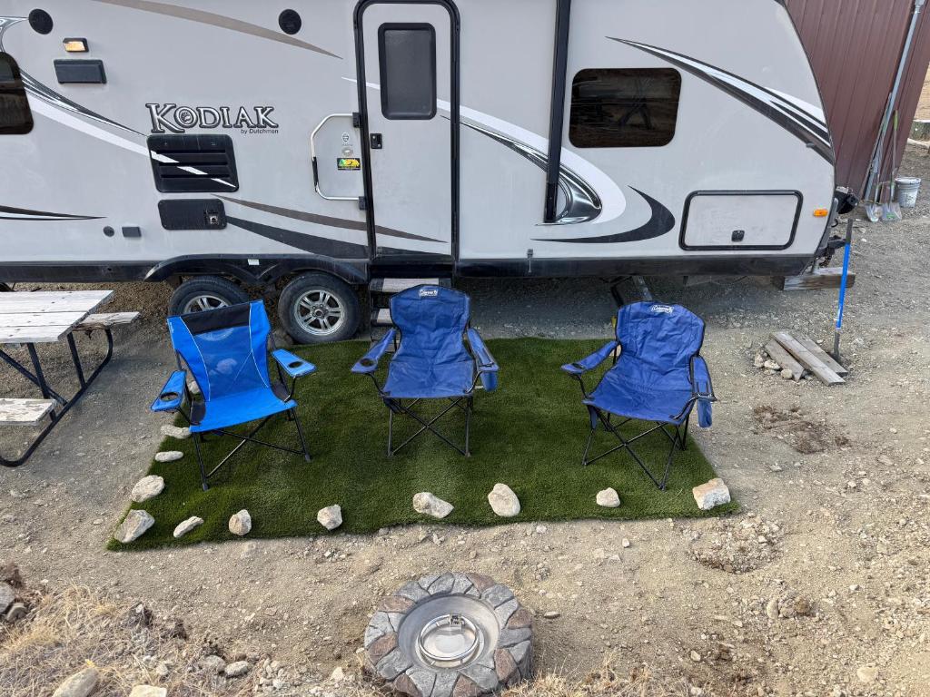 eine Gruppe von drei Stühlen und ein Anhänger in der Unterkunft Camper Adventure in Livingston