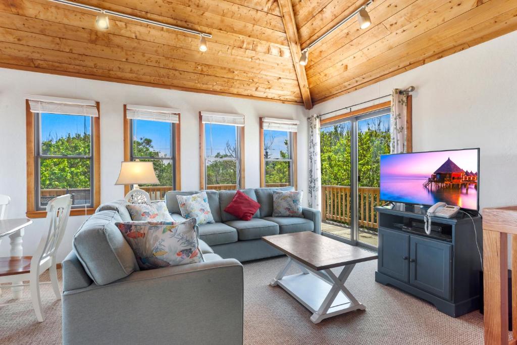 ein Wohnzimmer mit Sofa und Fernseher in der Unterkunft 1100 - La Maison De Geezer in Corolla