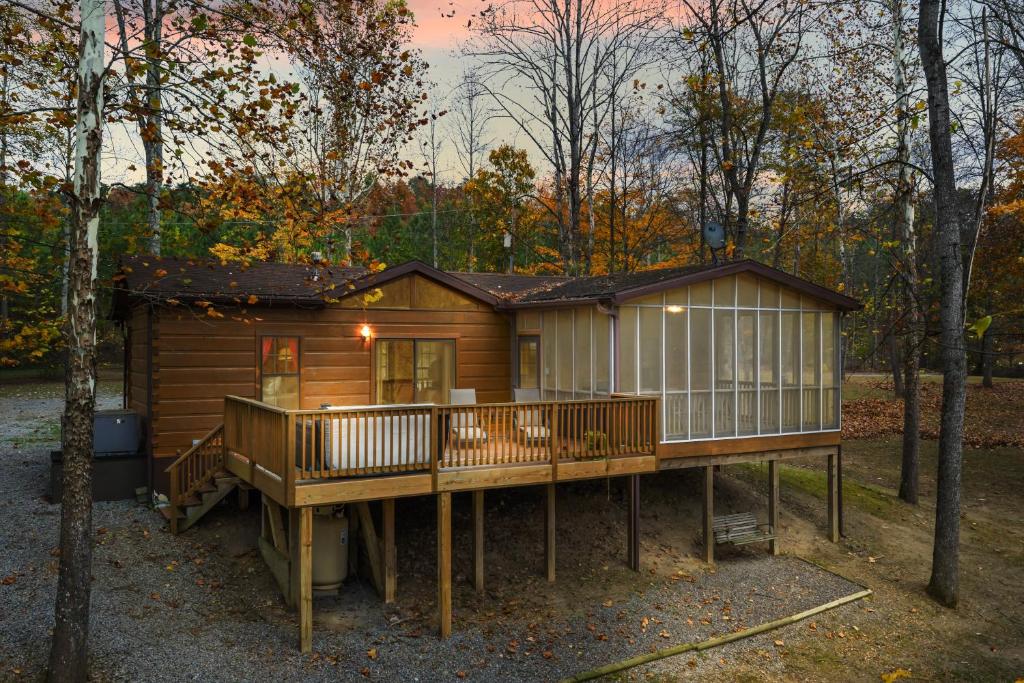 a cabin in the woods with a large deck at Sleepy Creek - Hot Tub, Pet Friendly, Creekside, Grill, Wifi, Fire Pit, Deck, Screen Porch, Family Friendly, Fishing, View, Games in Berkeley Springs