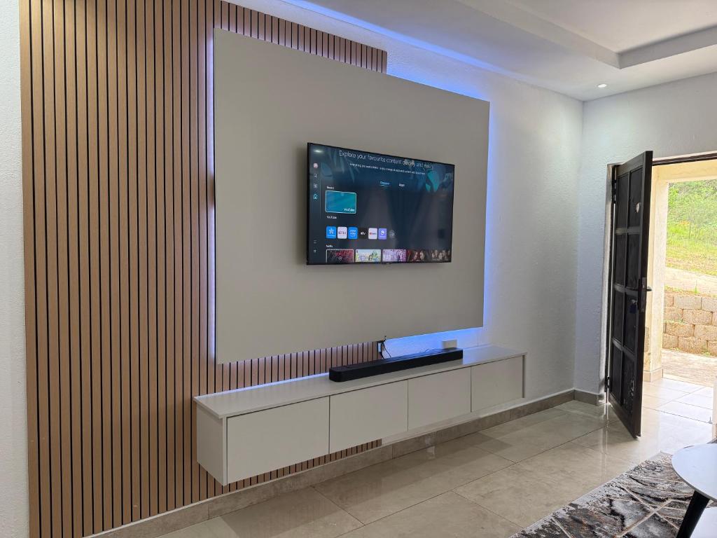 ein Wohnzimmer mit einem Fernseher an der Wand in der Unterkunft Hippoville in Mbabane