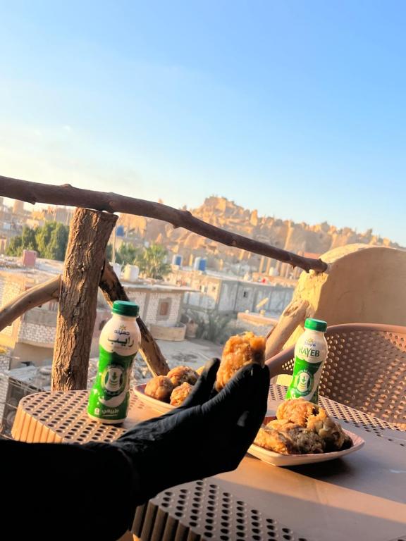 a person holding a plate of food and two bottles of beer at RAAK HOTEL فندق راك in Siwa