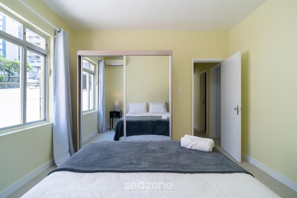 a bedroom with a large bed and a mirror at Aptos completos com localização privilegiada no coração de Floripa – CSNs in Florianópolis