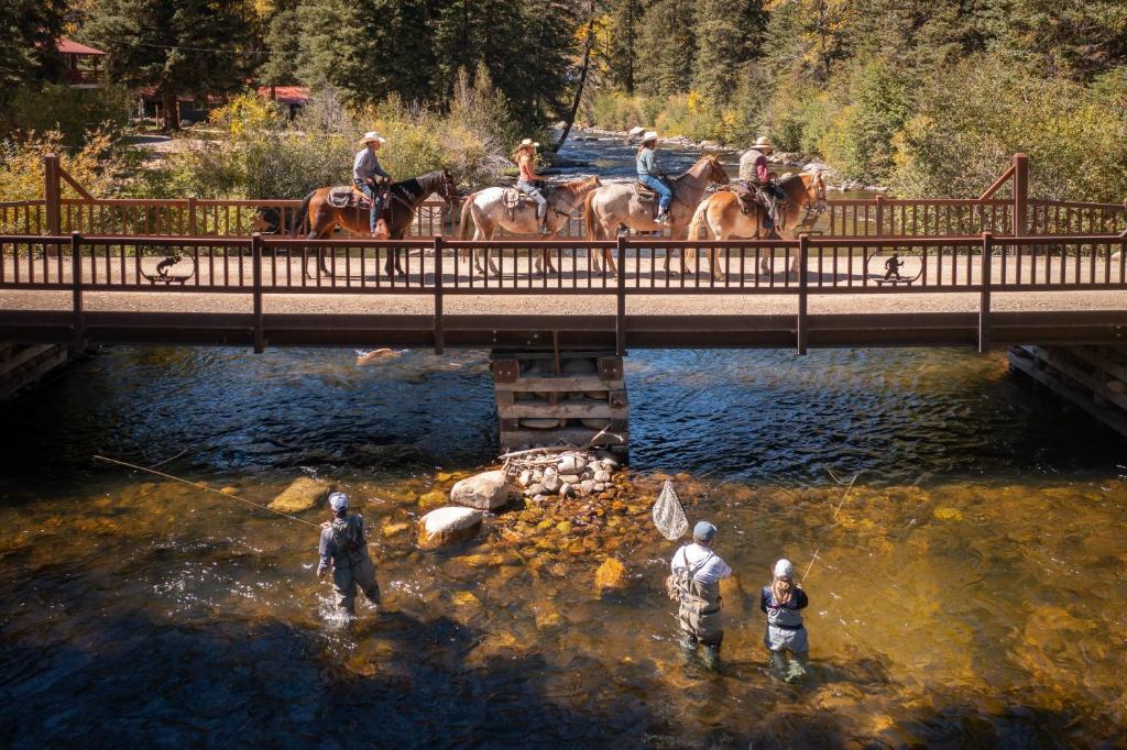 a group of people riding horses over a bridge at Harmels on the Taylor in Almont