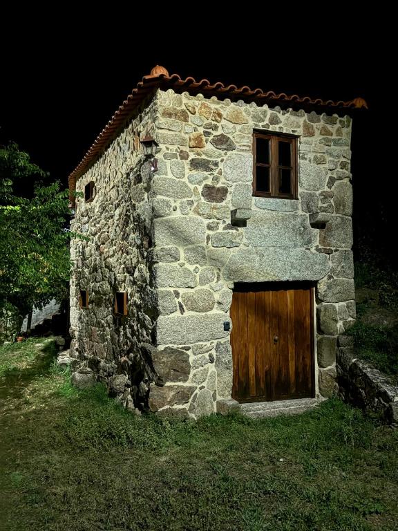 a stone building with a wooden door and a window at Sidrós Houses in Vila Nova