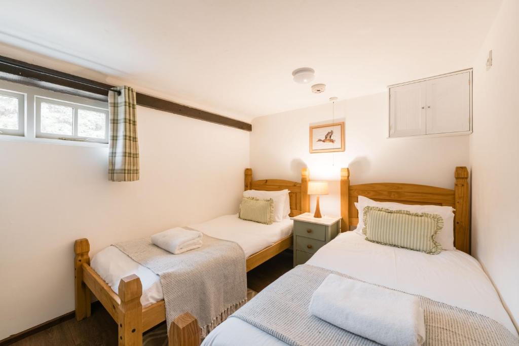 ein Schlafzimmer mit zwei Betten und einem Fenster in der Unterkunft The Henloft Cotswolds Farm Stay With Pool in Lechlade