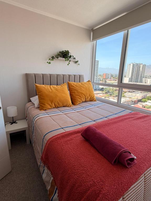 Un dormitorio con una cama con almohadas naranjas y una ventana. en Departamento rancagua centro nuevo, en Rancagua