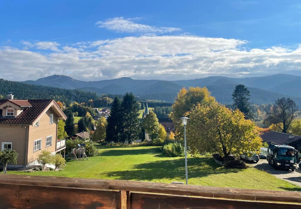 ein Haus mit einem grünen Hof mit Bergen im Hintergrund in der Unterkunft Ferienwohnung Müller - Arberblick in Lohberg