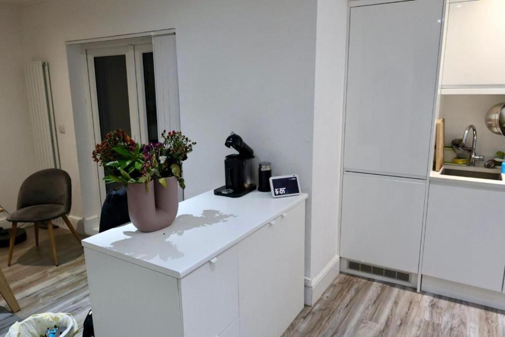 a white kitchen with a vase of flowers on a counter at The ChurchHill in East Barnet