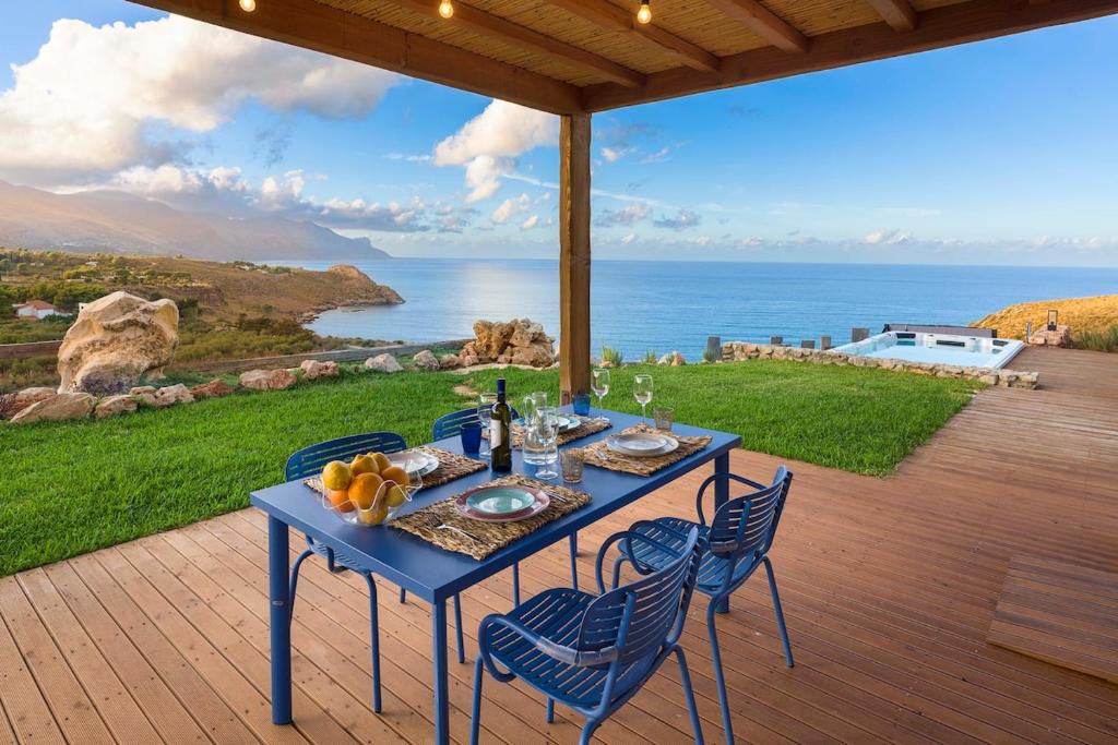 a blue table and chairs on a patio with a view of the ocean at Villa Corallo Cala Bianca in Castellammare del Golfo