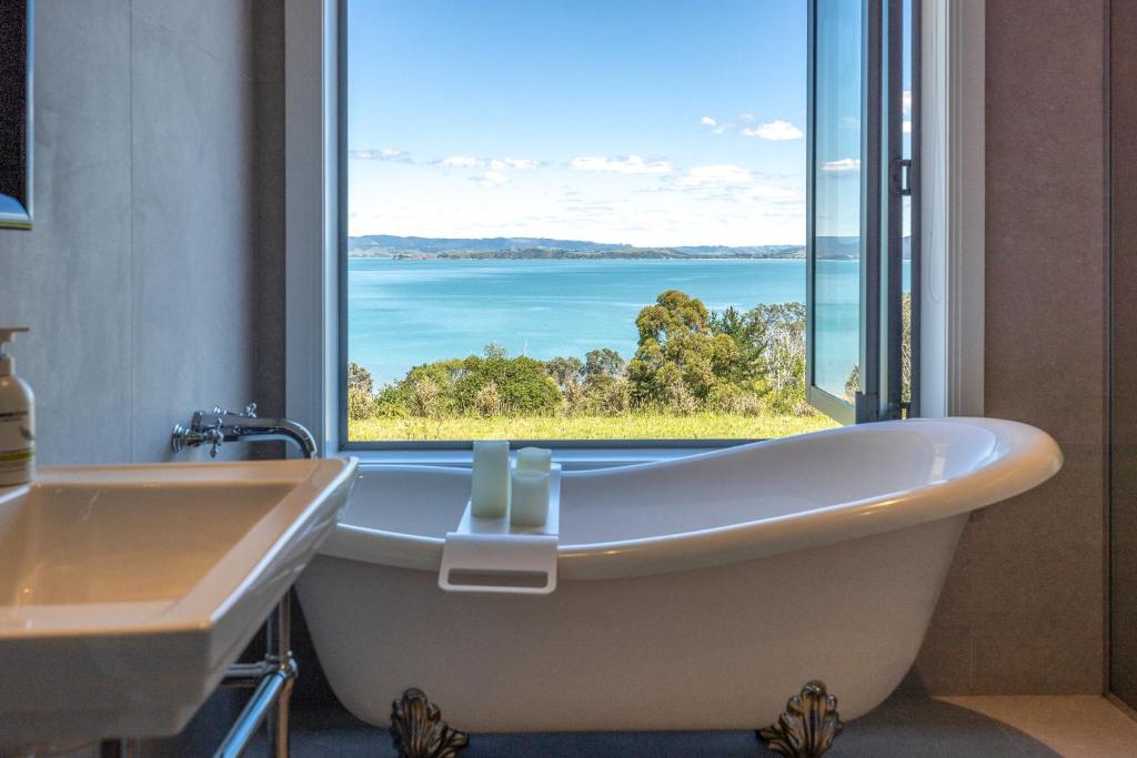 uma banheira em um banheiro com uma janela grande em The Keep at Woodside Bay em Waiheke Island