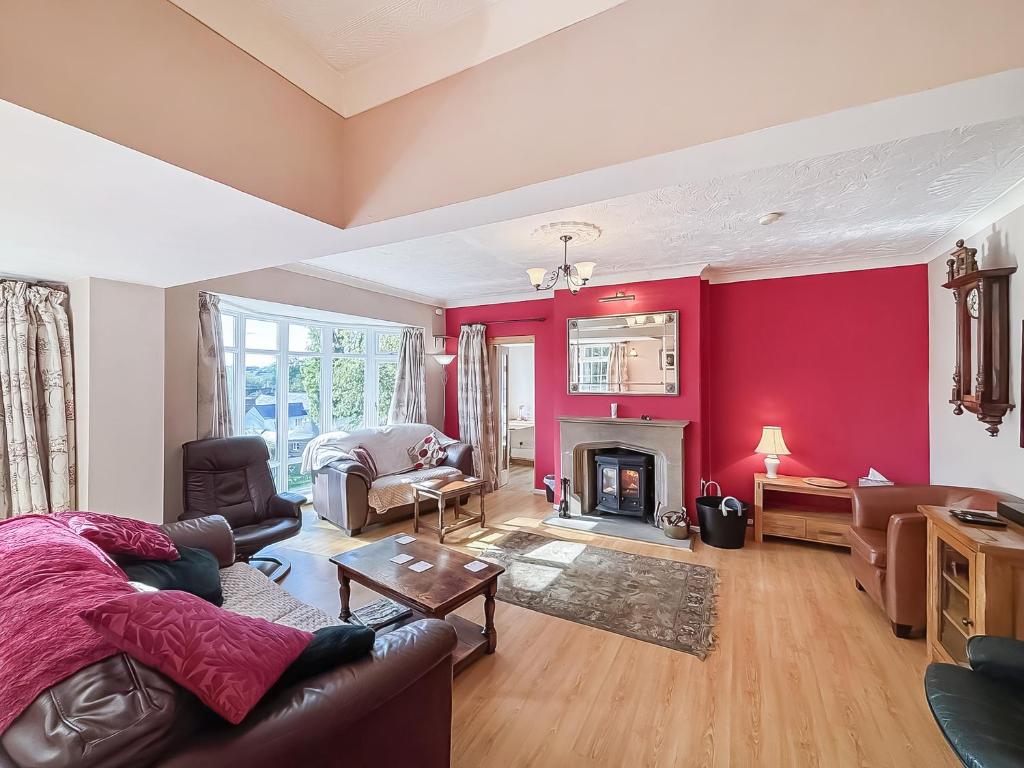ein Wohnzimmer mit roten Wänden und einem Kamin in der Unterkunft Brithdir in Leighton