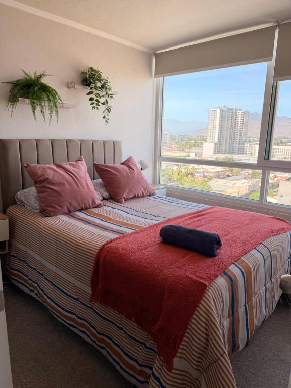 une chambre avec un grand lit avec une grande fenêtre dans l'établissement Vista de la cuidad céntrica, ubicado a pasos del mall , restaurantes con excelentes conectivilidad, à Rancagua
