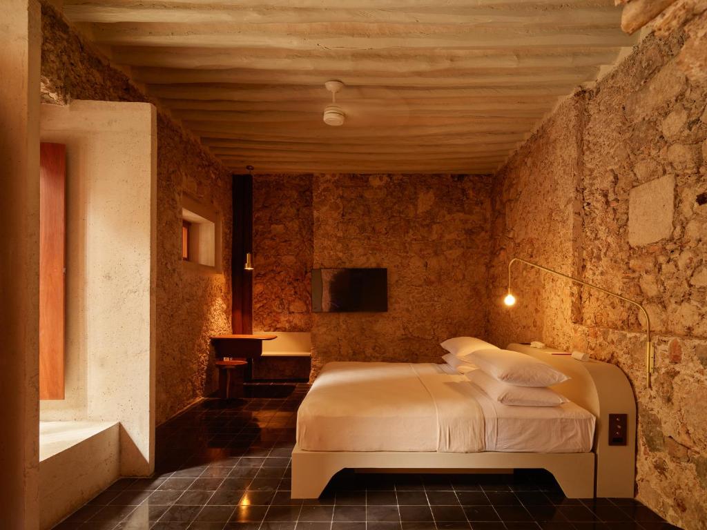 a bedroom with a bed in a stone wall at Hotel Sevilla in Mérida