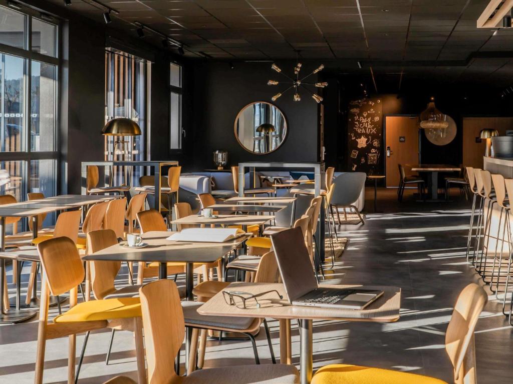 un restaurant avec des tables et des chaises avec un ordinateur portable dessus dans l'établissement ibis Saint Paul Trois Chateaux, à Saint-Paul-Trois-Châteaux