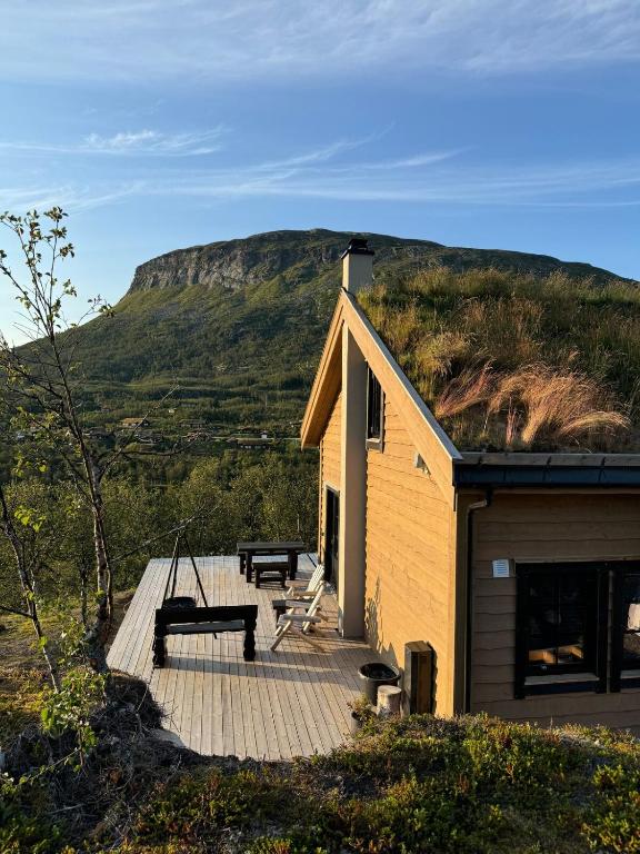 a house with a bench on a deck with a hill at Fjellperlen, Hardangervidda in Eidfjord