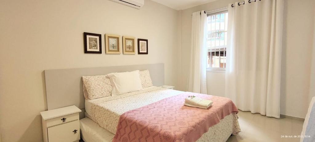 apto 4 quartos 50 metros da praia في باليريو كامبوريو: غرفة نوم بسرير وبطانية وردية ونافذة