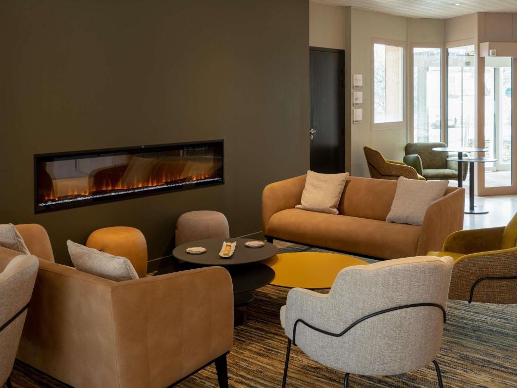 uma sala de estar com sofás e uma lareira em Mercure Auxerre Autoroute du Soleil em Appoigny