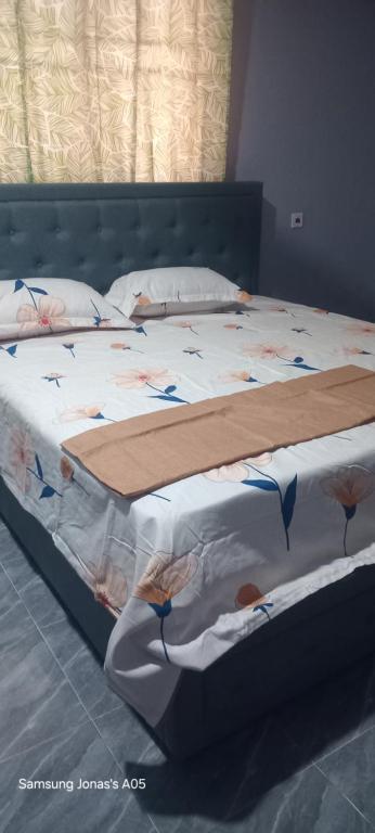 - une chambre dotée d'un lit avec des draps blancs et des fleurs dans l'établissement NEO HOME Gbawe, à Gbawe
