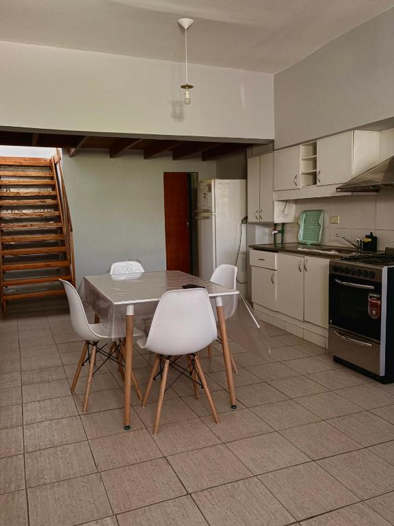 eine Küche mit einem Tisch und weißen Stühlen in der Unterkunft Departamento simple y cómodo en Cipolletti in Cipolletti