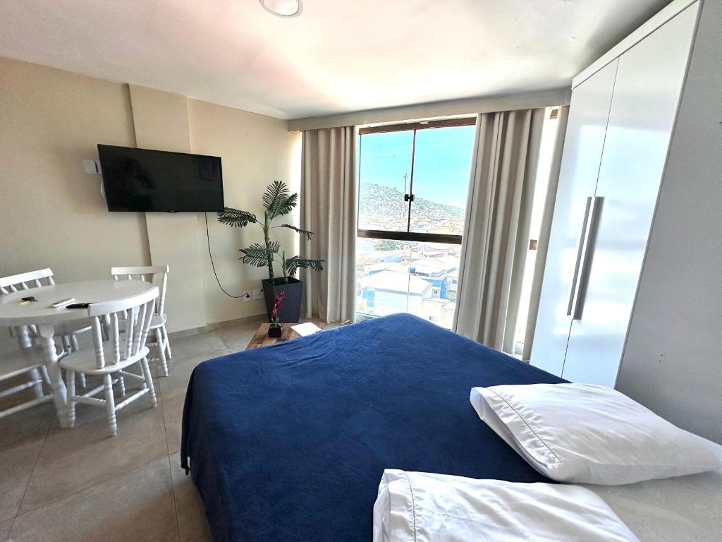 a bedroom with a bed and a table and a television at Eu Amo Arraial Hospedagem - Sophia I Orla Praia Grande in Arraial do Cabo