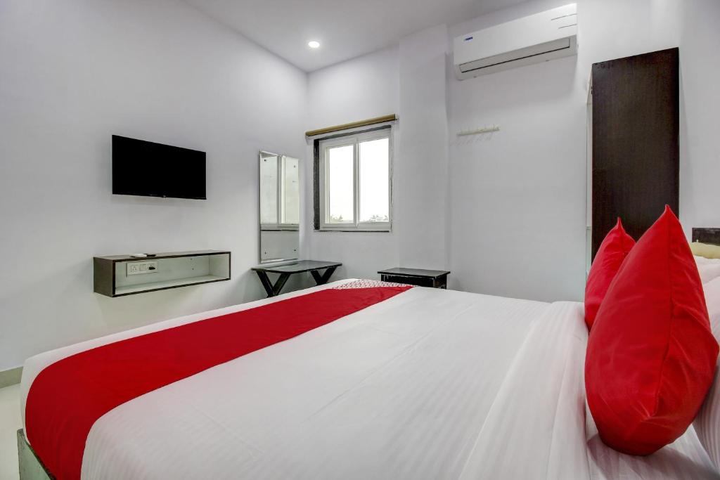 OYO Flagship Grand Mythri في Maula Ali: غرفة نوم بسرير أبيض كبير مع وسائد حمراء